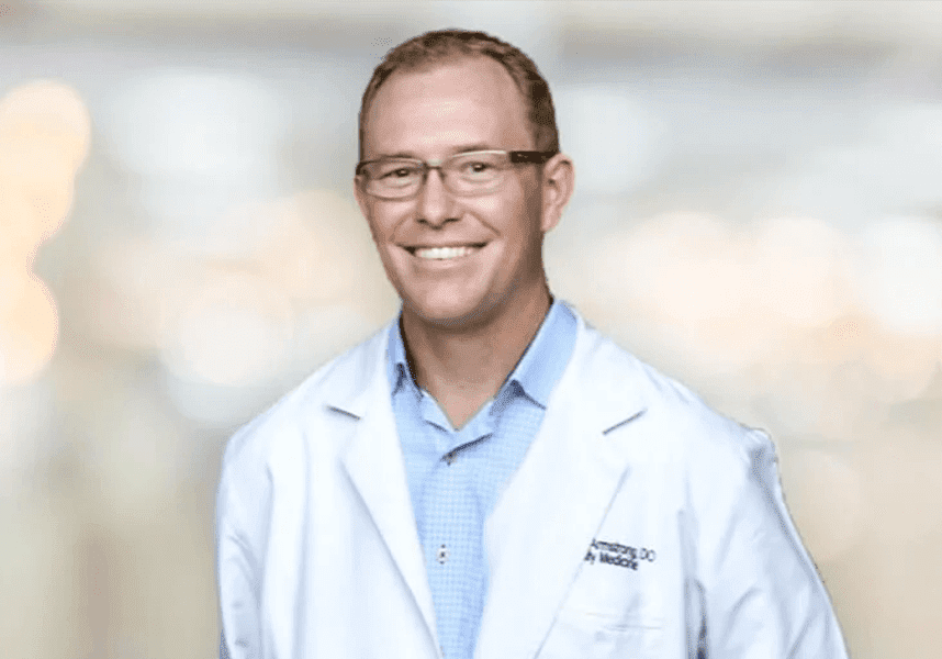 1126652 A man in white coat and glasses smiling for the camera.